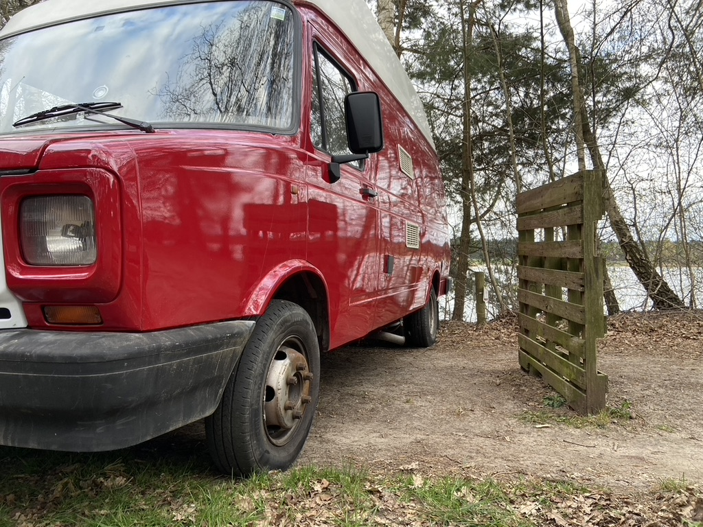 Rode DAF 400 camper aan het water in het bos